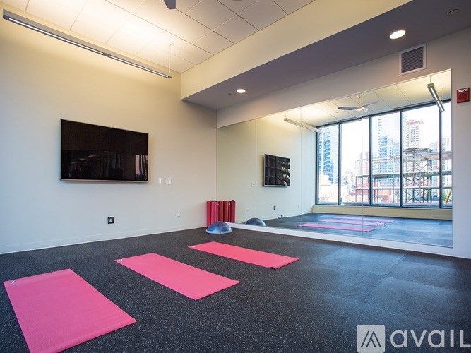 A yoga studio with pink mats and a television on the wall.