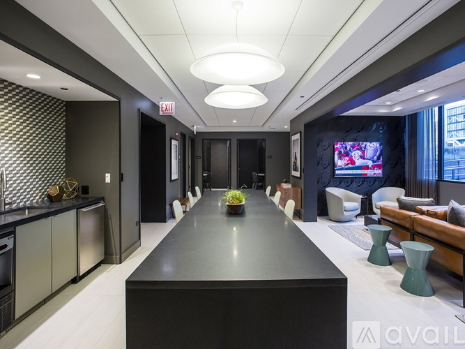 A modern kitchen with a long black table in the middle.