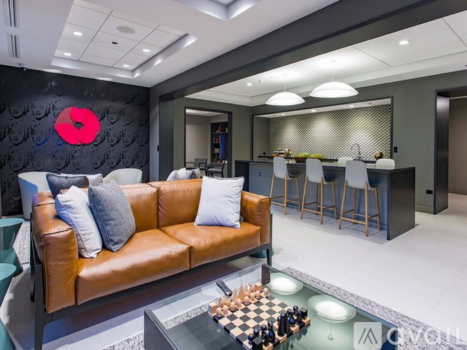 A living room with a brown leather couch and a chess board on the coffee table.