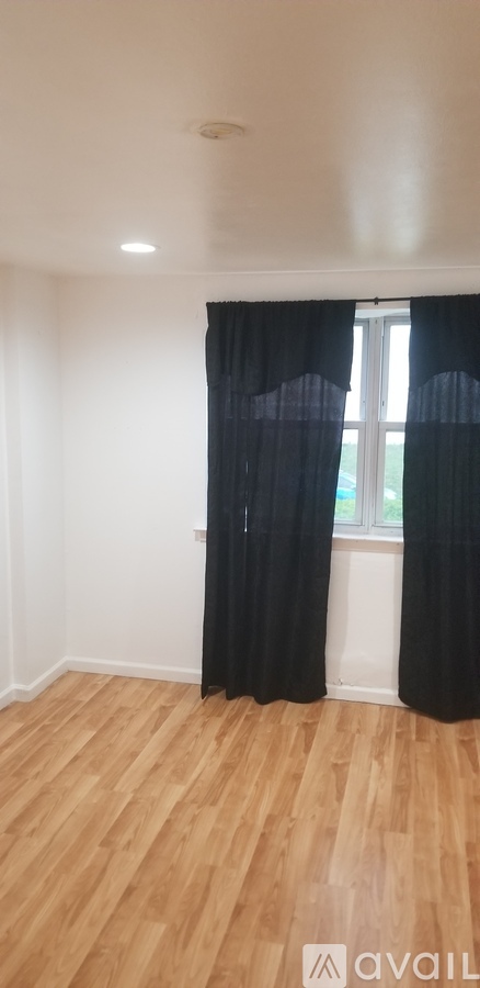 A room with wooden flooring and black curtains.