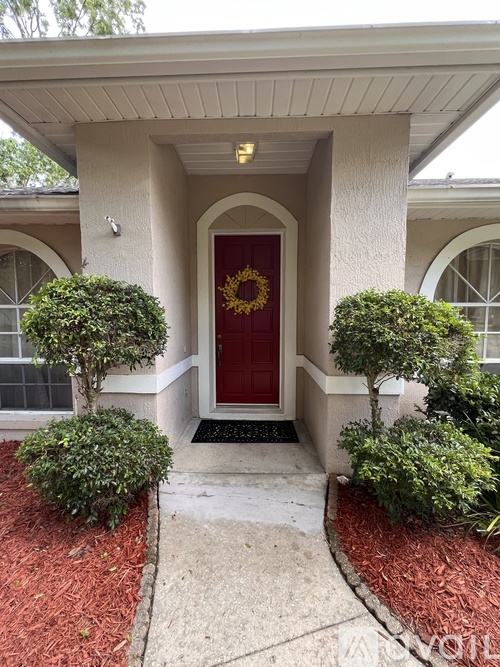 A red door with a silver handle and a black doormat with white designs on it.