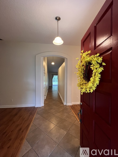A spacious room with wooden floors and a large window with a view of a green lawn.