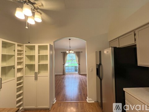 A kitchen with a refrigerator, cabinets, and a ceiling fan.
