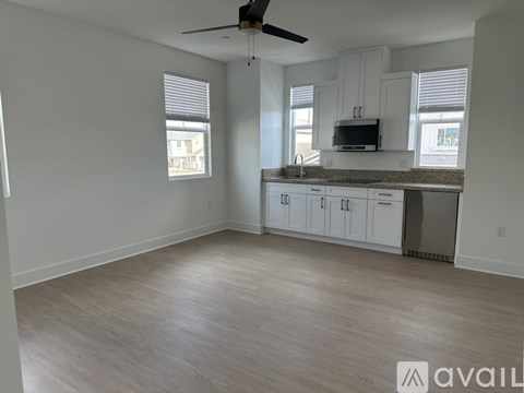 A kitchen with a fan and wooden flooring.