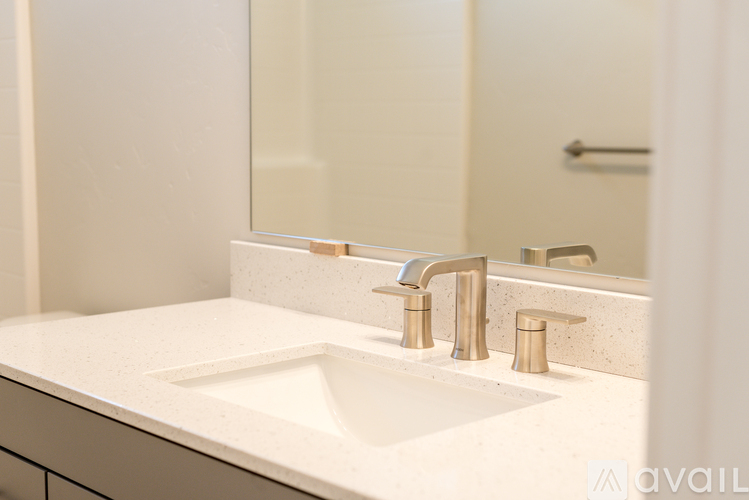 A bathroom sink with a gold faucet and a mirror above it.