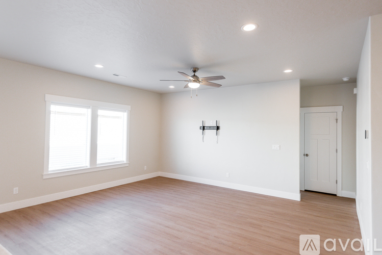 A spacious room with a ceiling fan and two windows.