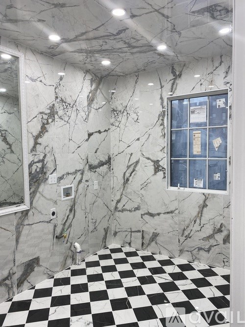 A bathroom with a checkered floor and marble walls.