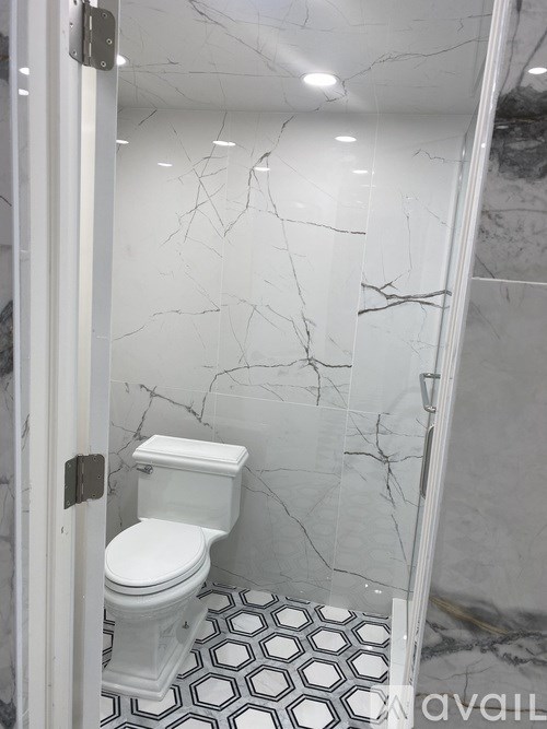 A white toilet in a bathroom with marble walls and floor.