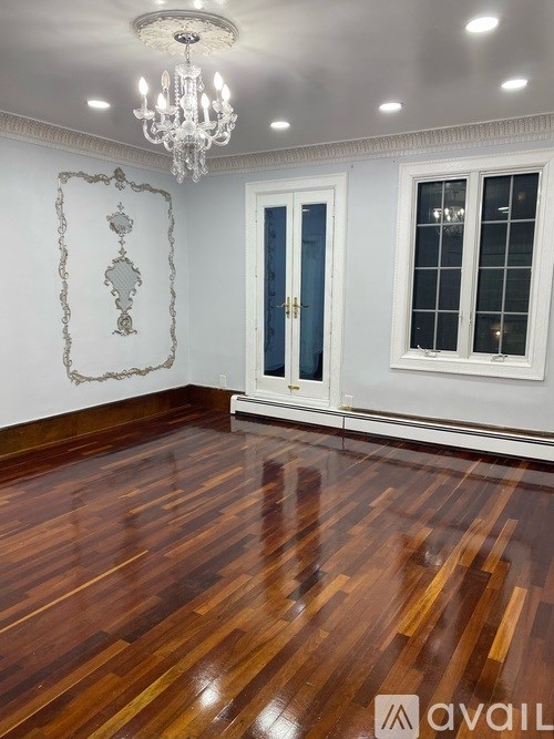 A room with a chandelier, hardwood floors, and a wall sconce.