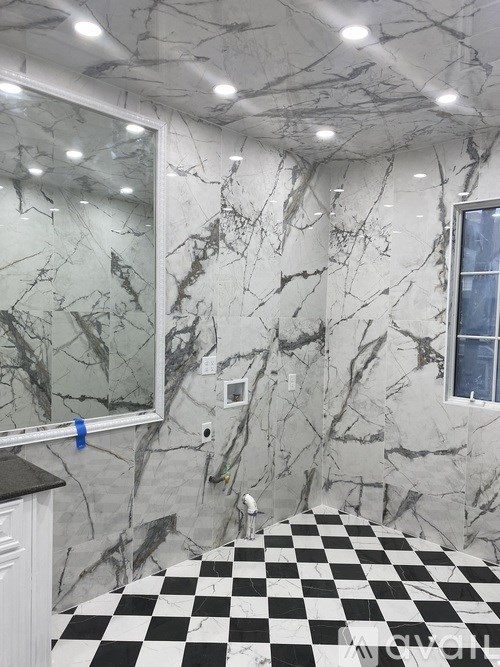 A bathroom with a checkered floor and marble walls.