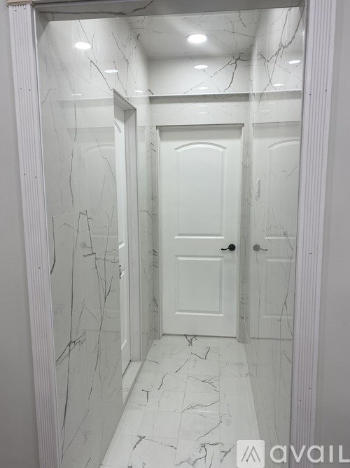 A hallway with a white door and marble flooring.