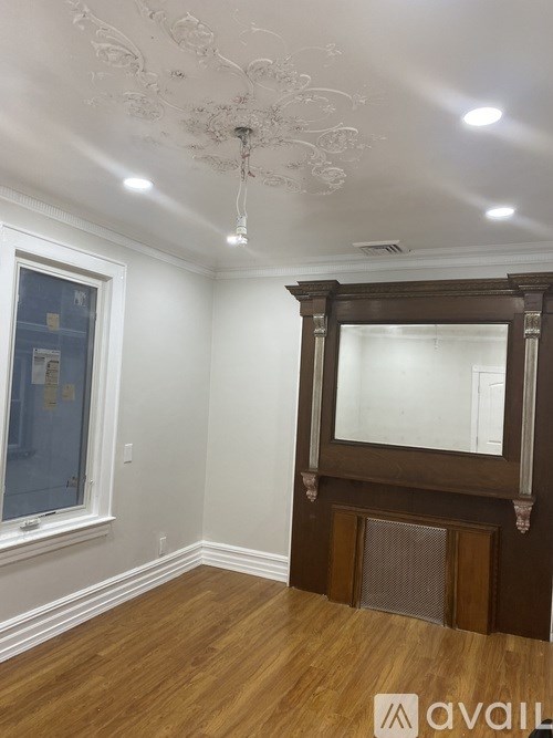 A room with a wooden floor and a large mirror on the wall.