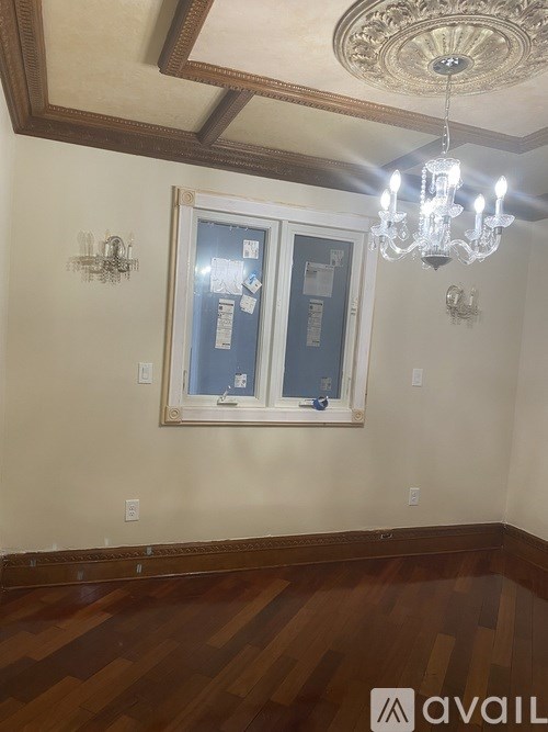 A room with a chandelier and a framed mirror on the wall.