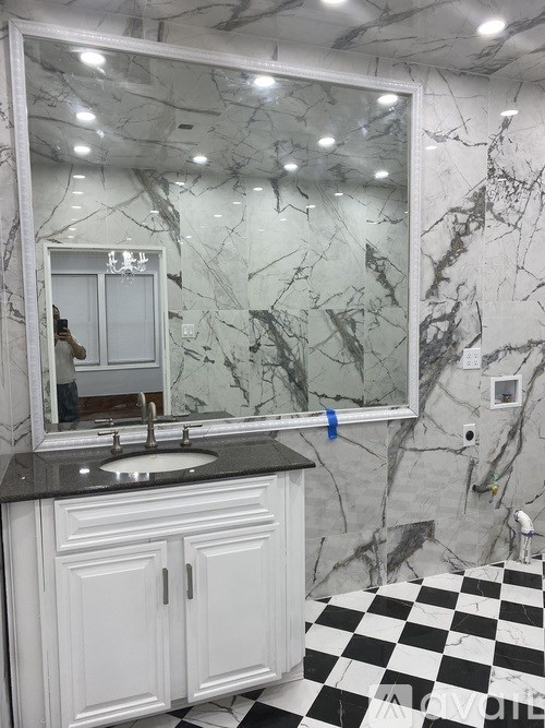 A bathroom with a marble wall and a checkered floor.