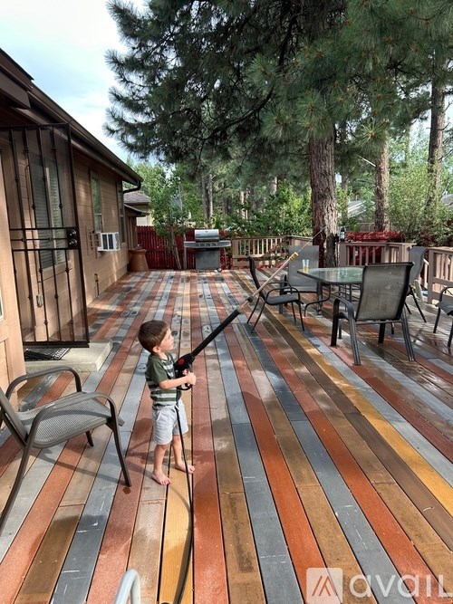 A boy is playing with a toy gun on a wooden deck.