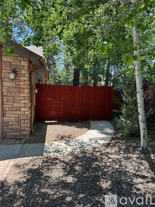 A red gate is closed at the entrance to a yard.