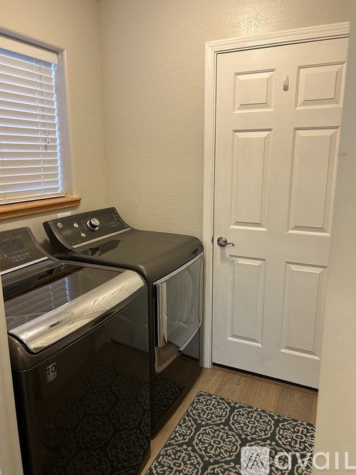 A black dishwasher is in a small kitchen next to a white door.