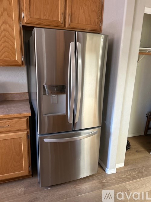A stainless steel refrigerator with a water and ice dispenser in the middle of the door stands in a kitchen.