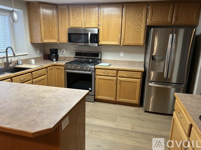 A kitchen with wooden cabinets and a stainless steel refrigerator.