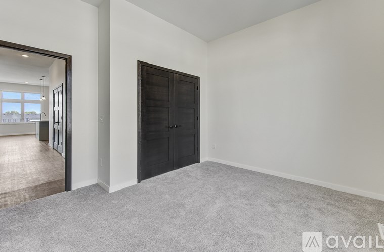 A room with a black door and a grey carpet.
