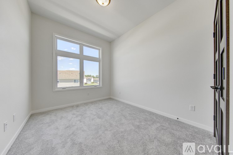 A room with a carpeted floor and a window overlooking a building.