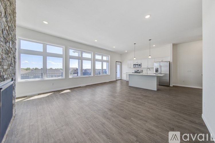 A spacious room with wooden flooring and large windows.