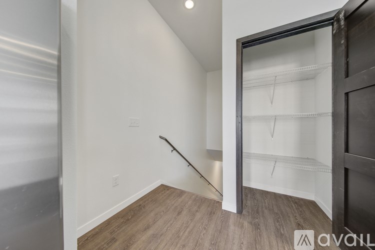 A room with a wooden floor and a white wall with a black door.