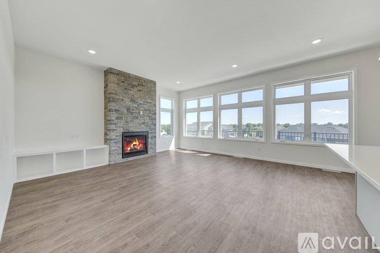 A spacious room with a stone fireplace and large windows.