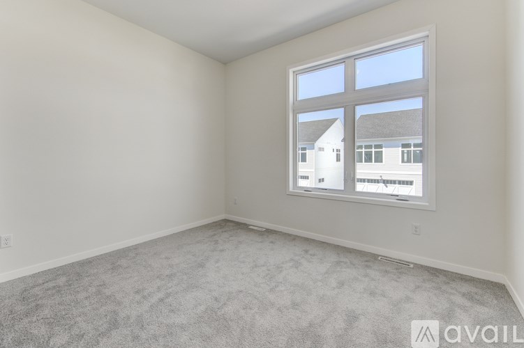 A room with a large window showing a view of a house across the street.