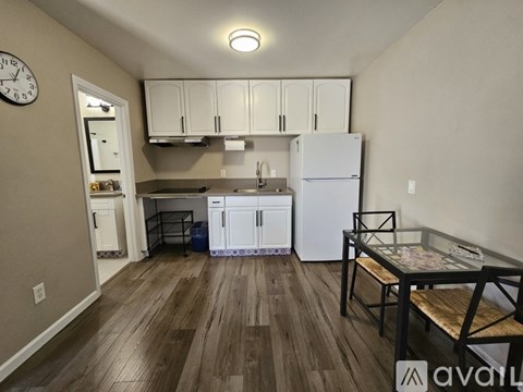 A kitchen with white appliances and wooden floors.