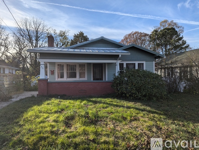 A house with a blue roof and a red brick foundation is for sale.