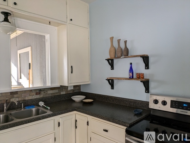 A kitchen with white cabinets and a black countertop.