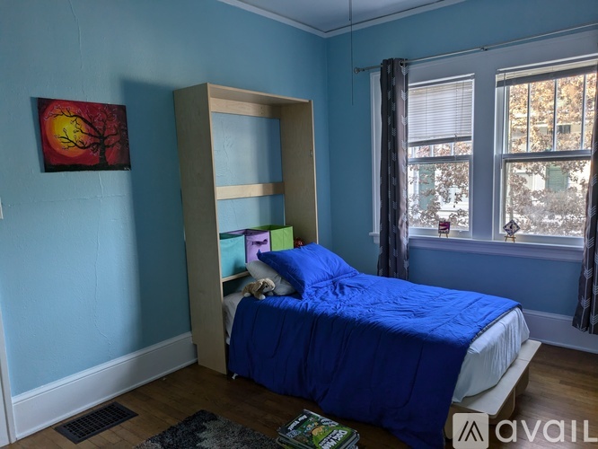 A bedroom with blue walls and a bed with a blue comforter.