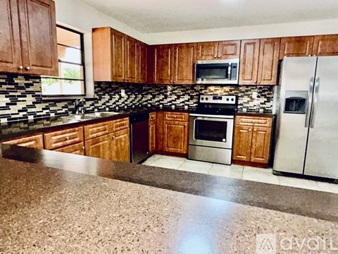 A kitchen with wooden cabinets and a black and white tiled backsplash.