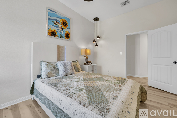 A bedroom with a bed, a painting, and a lamp.