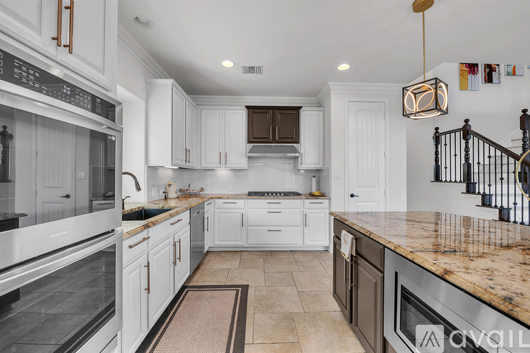 A kitchen with white cabinets and a marble countertop.