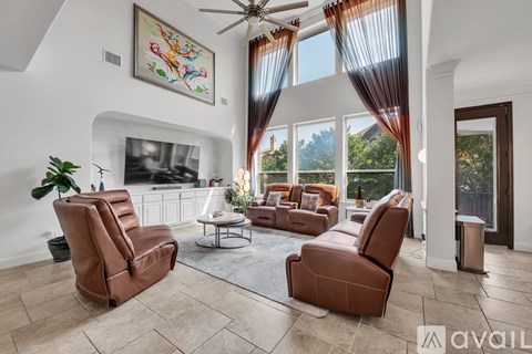 A living room with brown leather furniture and a ceiling fan.