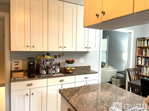 A kitchen with white cabinets and granite countertops.