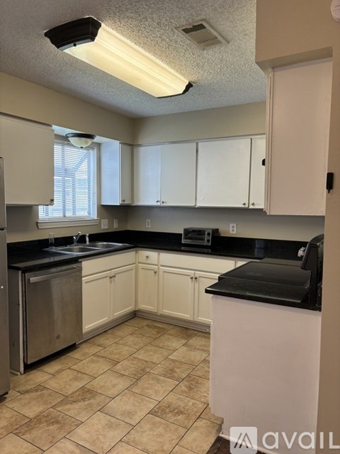 A kitchen with black countertops and white cabinets.