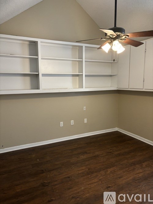 A room with a ceiling fan and wooden flooring.