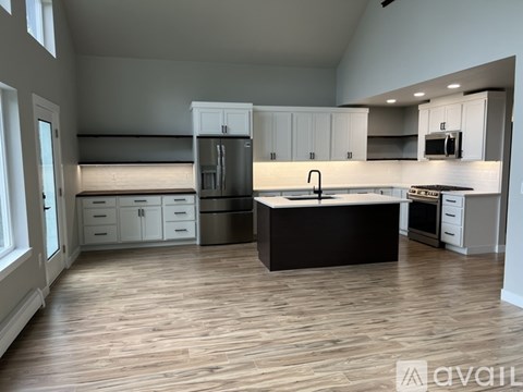 A spacious kitchen with wooden floors and white cabinetry.