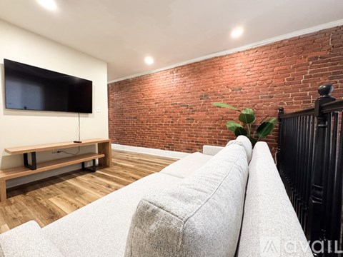 A living room with a grey couch and a flat screen TV on a wooden stand.