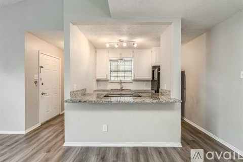 A kitchen with a marble countertop and wooden flooring.