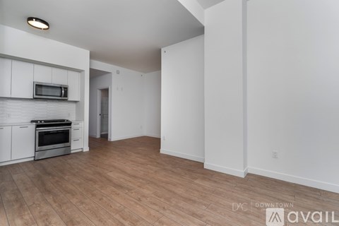 A spacious kitchen with white cabinets and a wooden floor.