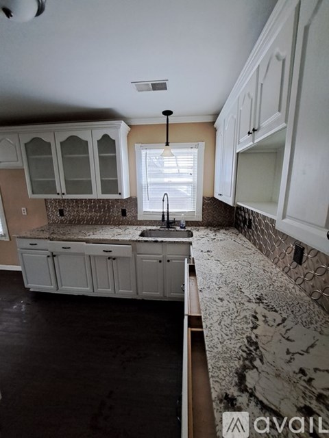 A kitchen with white cabinets and a marble countertop.