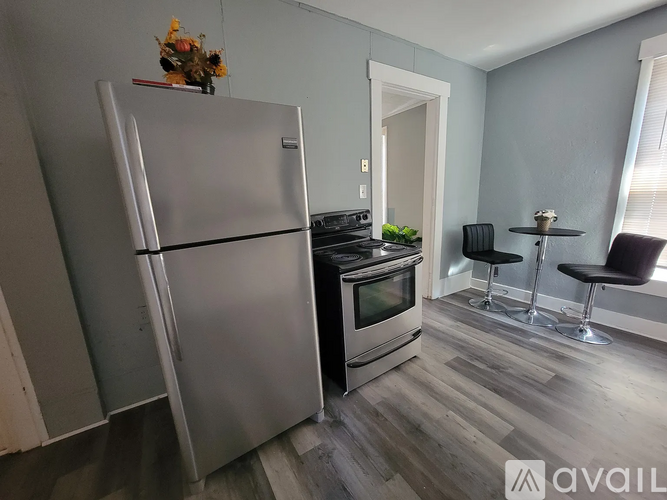 A kitchen with a refrigerator, oven, and a dining table with chairs.