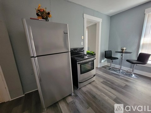 A kitchen with a refrigerator, oven, and a dining table with chairs.