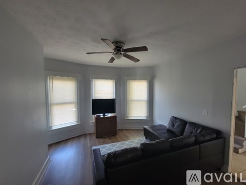 A living room with a black couch and a ceiling fan.