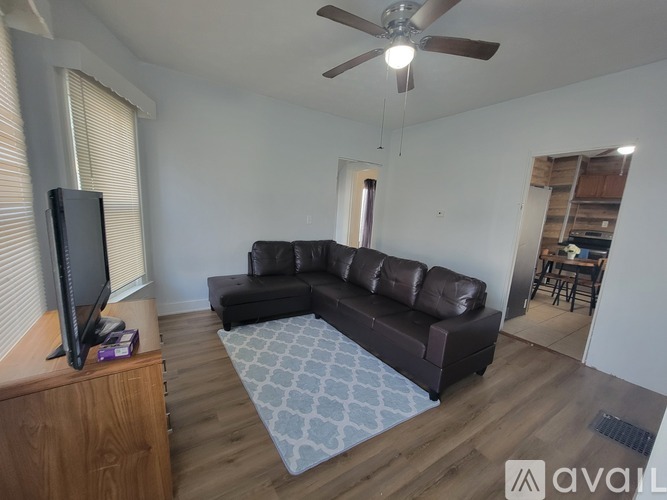 A living room with a brown leather couch and a ceiling fan.
