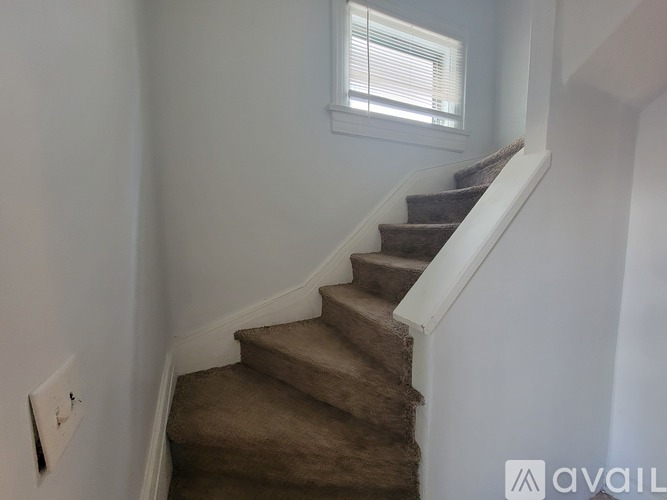A staircase with a carpeted runner and white risers.